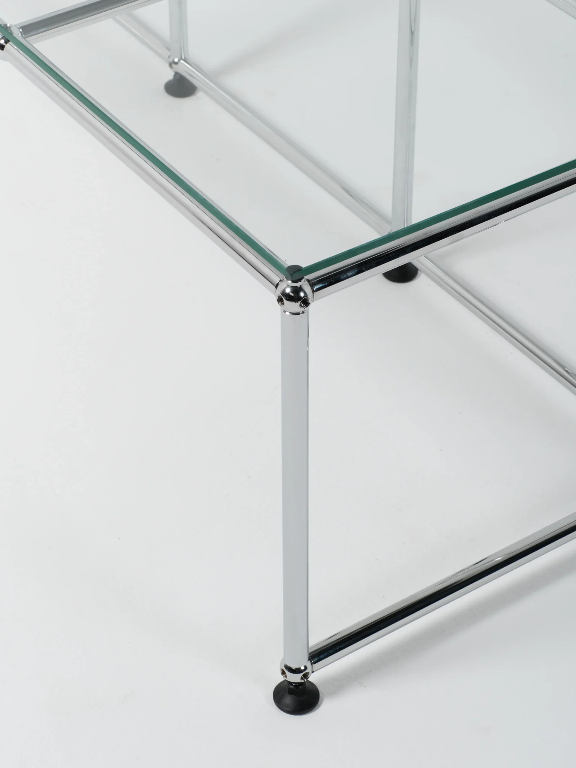 Corner of a glass-topped unit showing the glass edge, chrome frame and glide foot